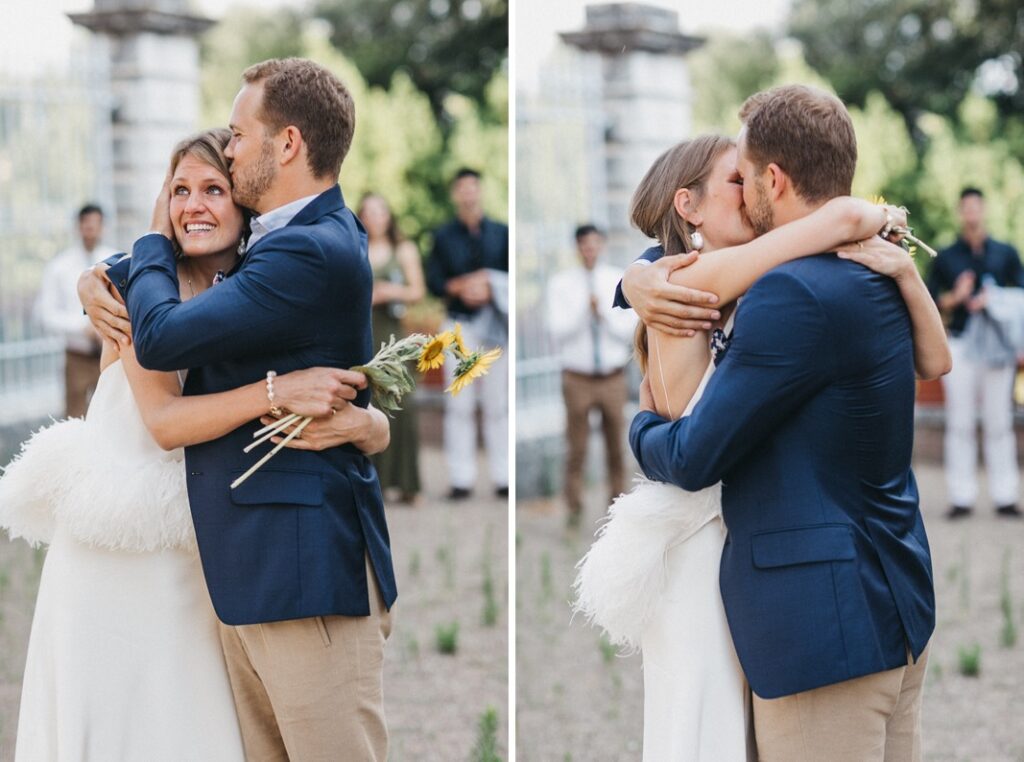 Eine Frau in einem rückenfreien, gefiederten Kleid geht Arm in Arm mit einem Mann in einem langärmeligen Hemd. Dieses Schwarz-Weiß-Bild wurde im Freien auf einer sonnenbeschienenen Straße aufgenommen und erinnert an die Eleganz einer Hochzeit in der Villa Cetinale.