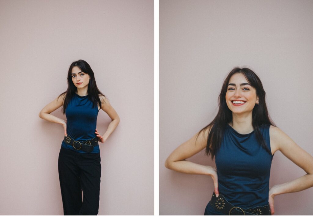 Eine Frau mit langen dunklen Haaren, die ein ärmelloses blaues Oberteil und eine schwarze Hose trägt, steht vor einer blassrosa Wand. Auf dem linken Foto der Fotografin sieht sie ernst aus, auf dem rechten Foto lächelt sie mit in die Hüften gestemmten Händen.