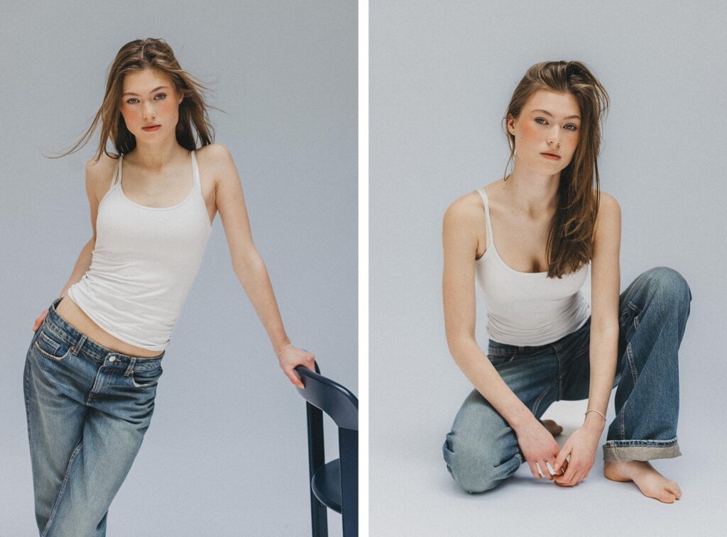 Eine junge Frau mit heller Haut und langen braunen Haaren, bekleidet mit einem weißen Tanktop und blauen Jeans, posiert in einem Studio. Aufgenommen von einem Fotografen Köln, lehnt sie in einer Aufnahme auf einem Stuhl, in der anderen kniet sie barfuß auf dem Boden.